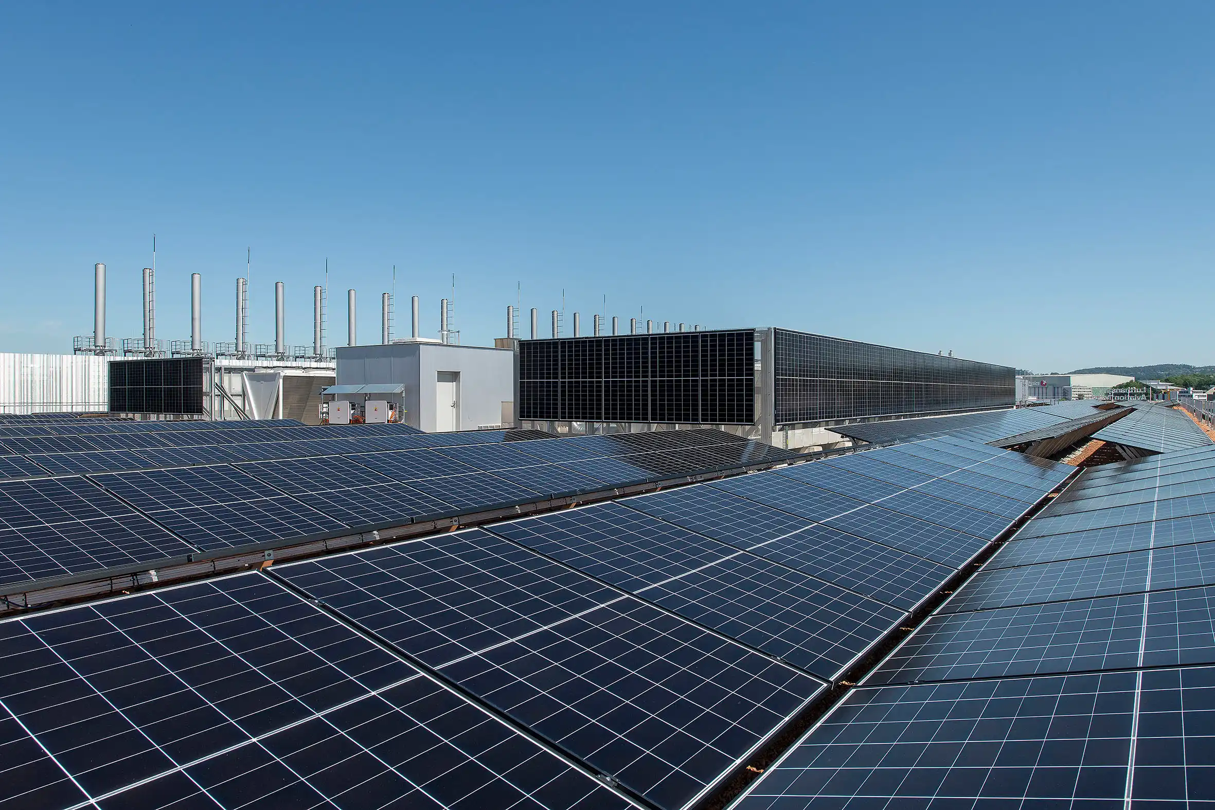 Rows of solar panels on a flat rooftop under a clear blue sky, ready to generate solar energy.