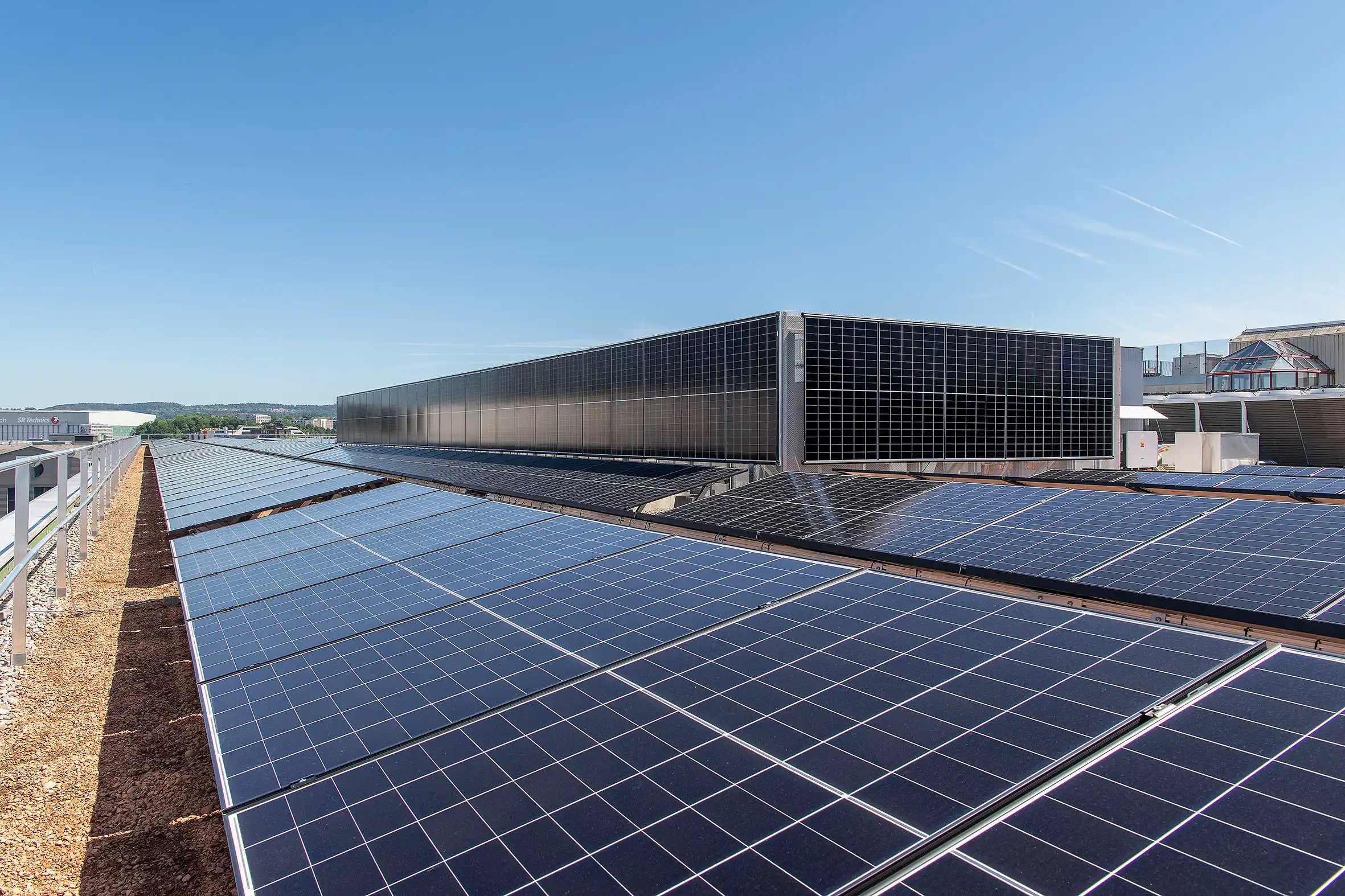 Rooftop solar panels covering a flat roof under a clear blue sky, generating renewable energy