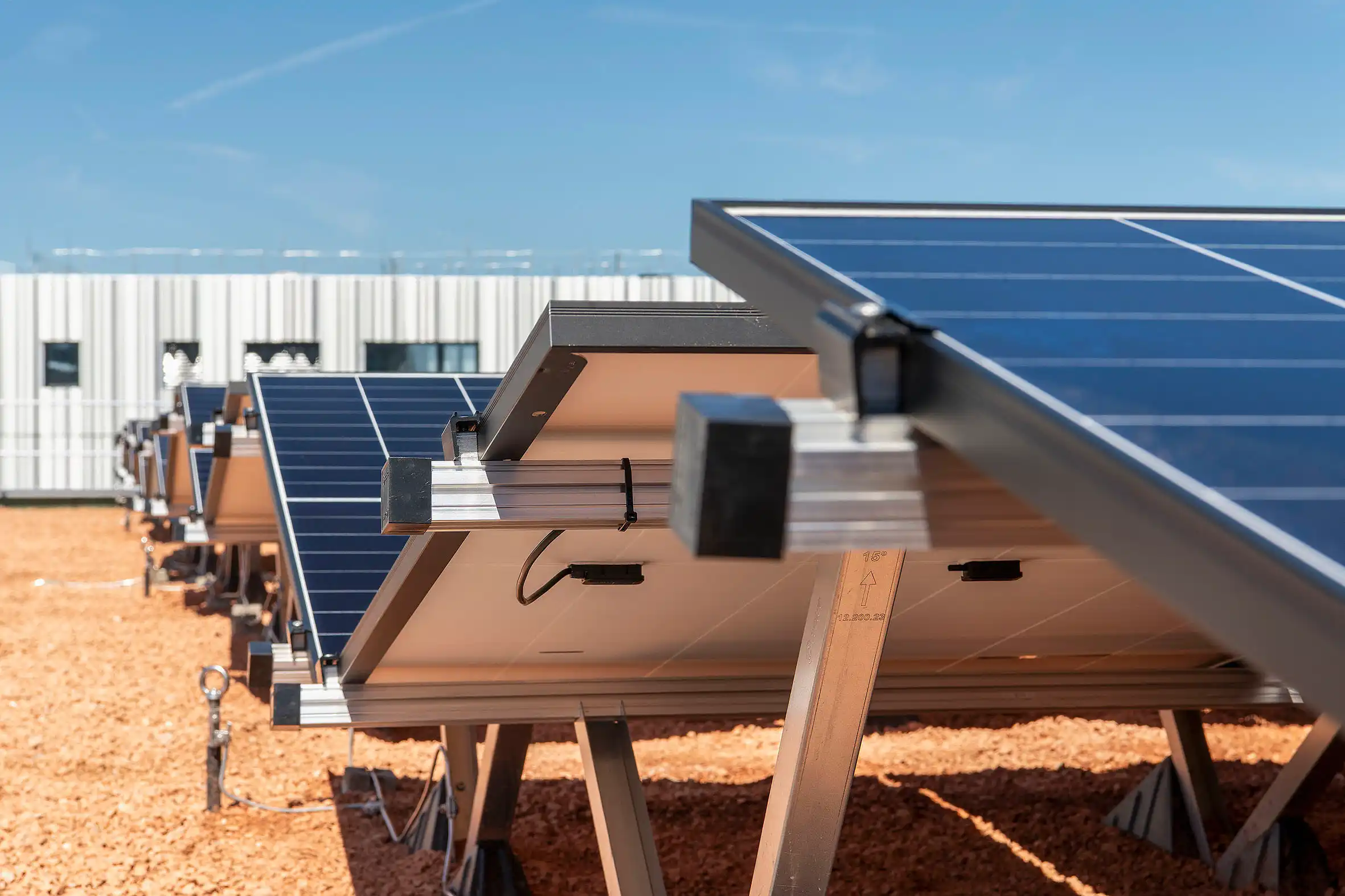 Row of solar panels on metal racks in a sunny solar farm field