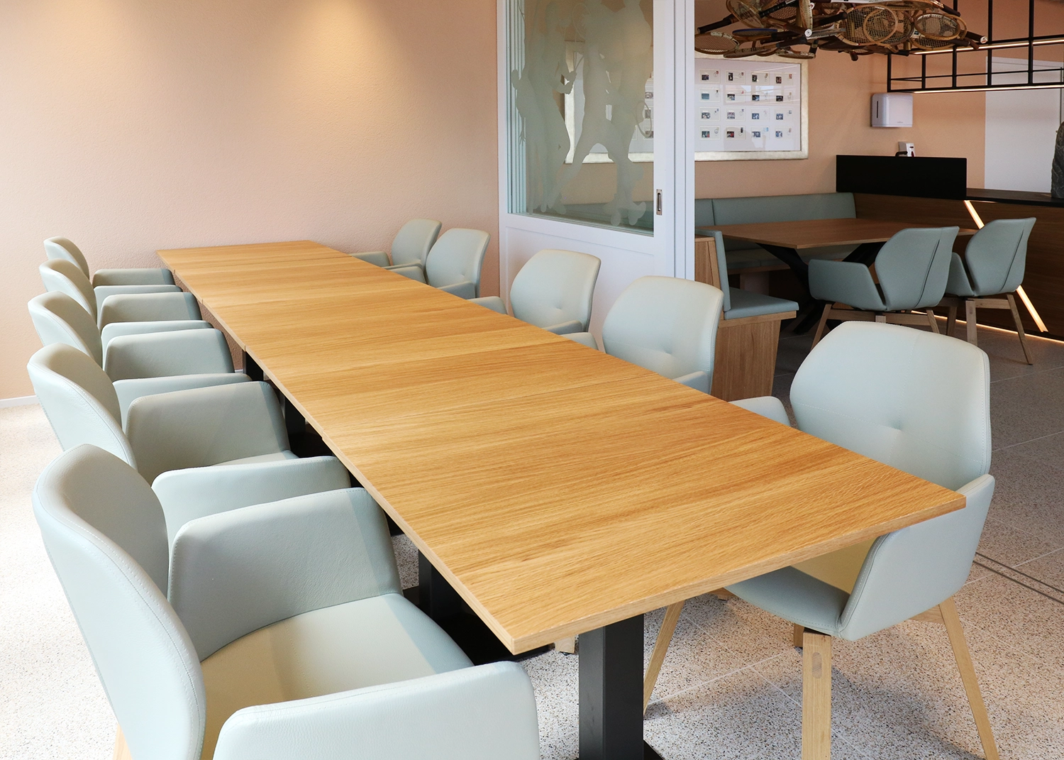 Long wooden conference table surrounded by light blue upholstered chairs in a modern meeting room.