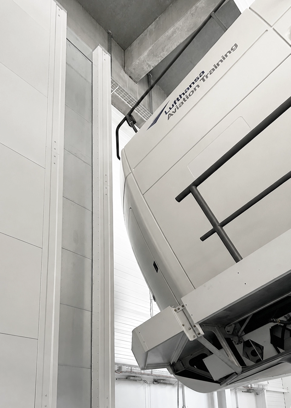 Large white aviation training device mounted diagonally in a hangar; branding reads 'Lighthouse Aviation Training'.